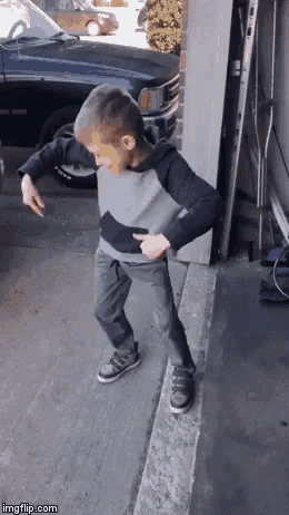 a young boy is dancing in front of a garage door .