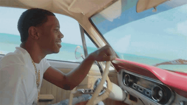 a man in a white shirt is driving a car with a red dashboard