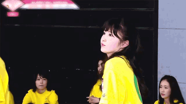 a girl in a yellow shirt is holding a sign that says ' a ' on it .
