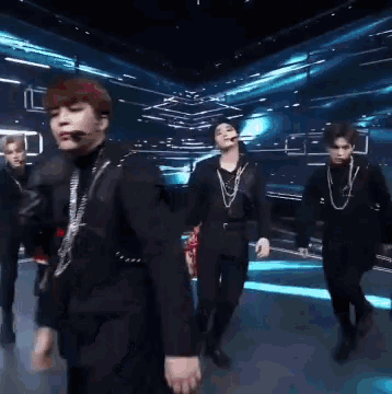 a group of men are dancing on a stage in front of a blue light .