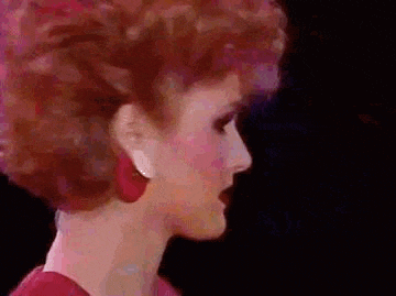a woman with red hair and red earrings is wearing a red dress and earrings .