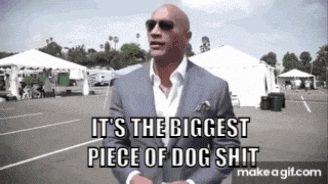 a man in a suit and sunglasses is standing in a parking lot and says it 's the biggest piece of dog shit .