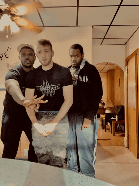 a man wearing a navy sweatshirt stands with two other men