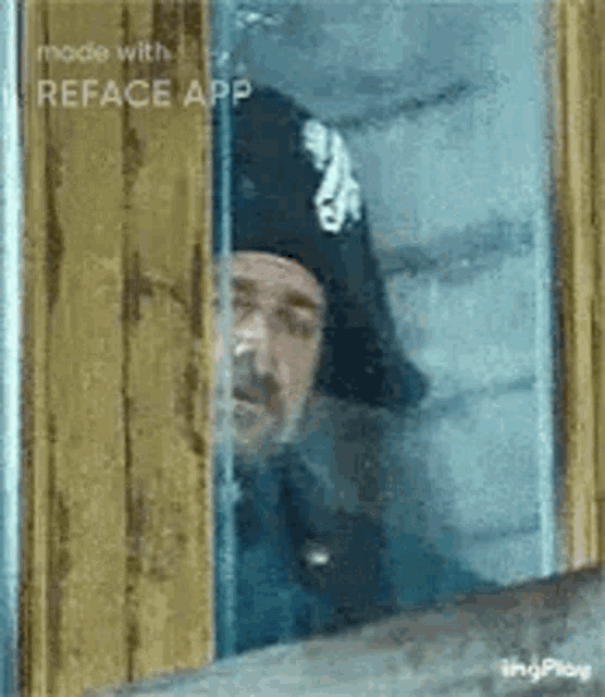 a man in a hat is peeking out of a window .