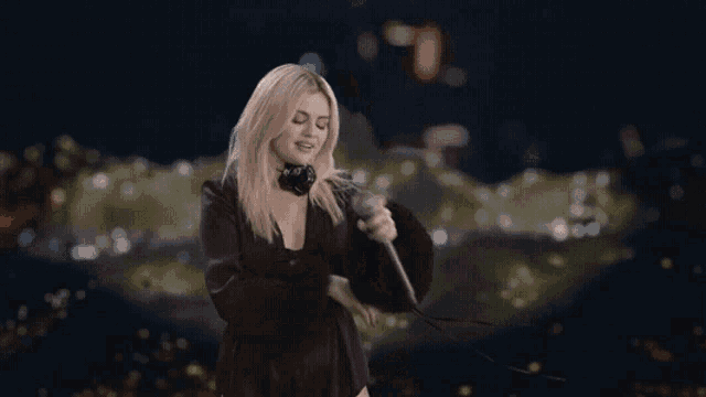 a woman singing into a microphone with headphones on