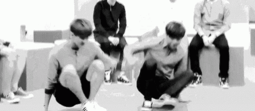 a group of young men are squatting down on the floor in a room .