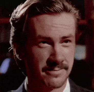a close up of a man 's face with a mustache and a suit .