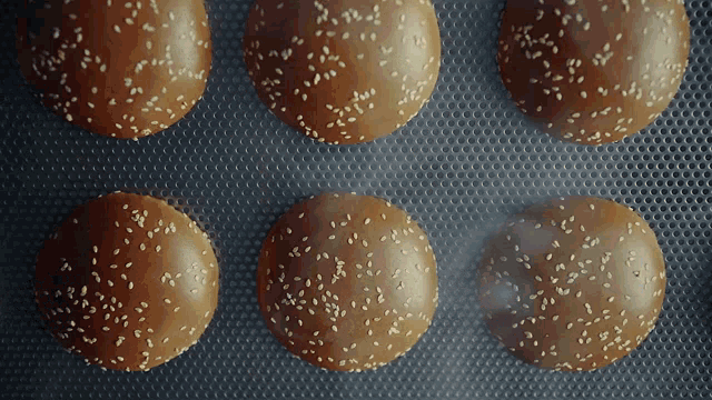 a bunch of hamburger buns with sesame seeds on them on a baking sheet