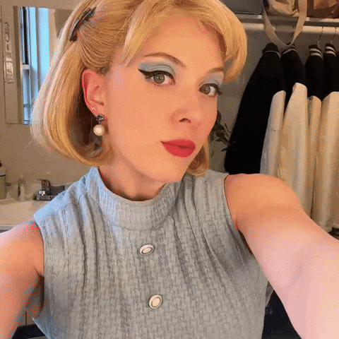 a woman taking a selfie with a blue eyeshadow and red lips