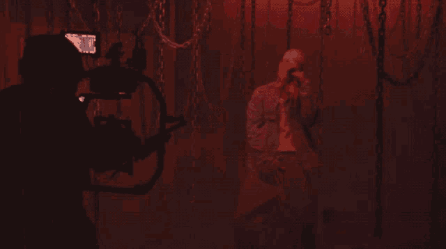 a man in a prison uniform is being filmed in a dark room