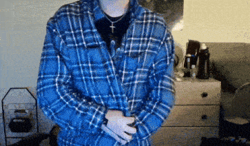 a man wearing a blue plaid shirt with a cross necklace