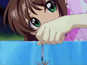 a girl with green eyes is holding a fishing hook in her hand