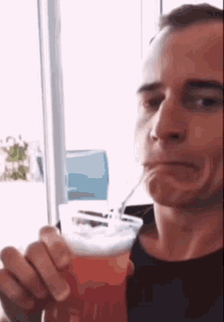 a man is drinking from a cup with a straw .