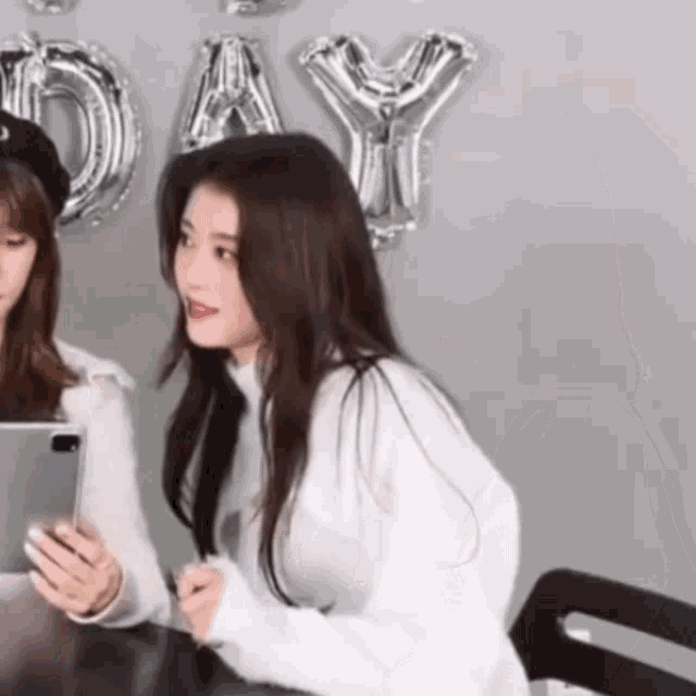 two girls are sitting at a table with balloons that say day