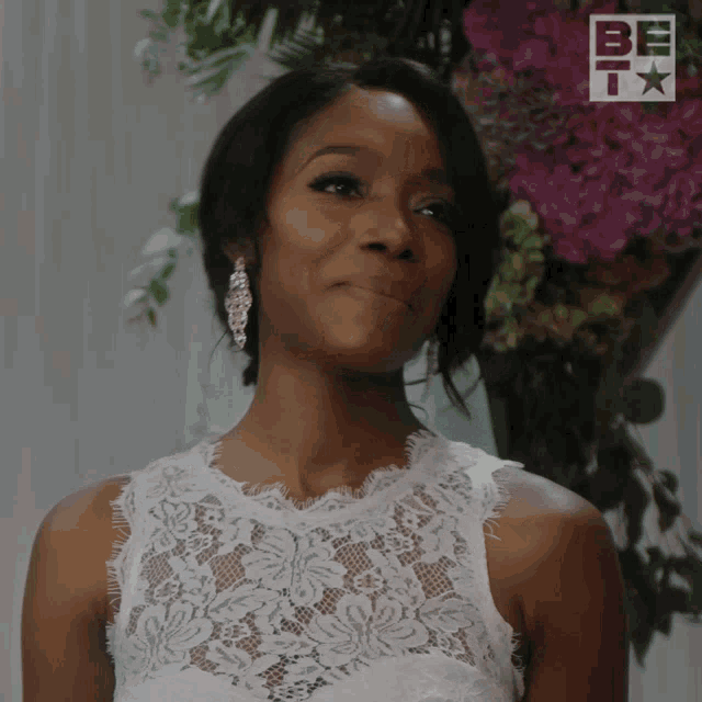 a woman in a white lace dress is smiling