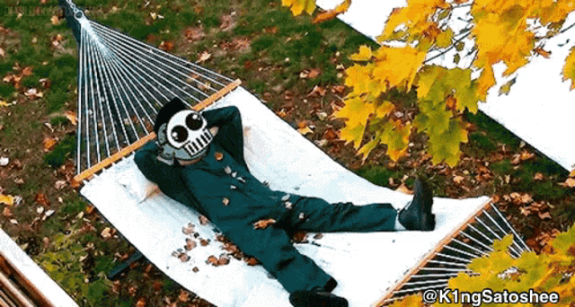 a person in a green jumpsuit is laying in a hammock with leaves on it