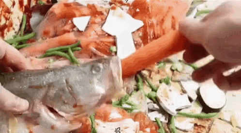 a person is cutting a fish on a pizza with a knife