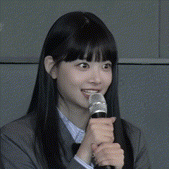 a girl with long black hair is holding a microphone and smiling .