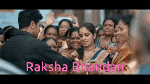 a man is standing in front of a crowd of people with the words raksha bhandand written above him .
