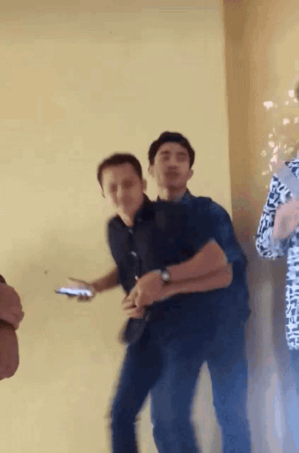 a man in a black shirt is holding another man 's arm in a room