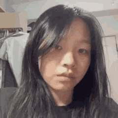 a young woman with long hair is taking a selfie in a room .