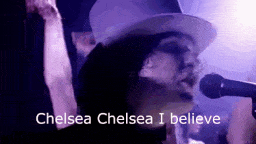 a man in a top hat singing into a microphone with the words chelsea chelsea i believe above him