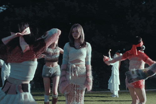 a group of women are standing in a circle and one of them is wearing a white top