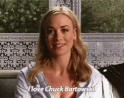 a woman is sitting in front of a window and smiling while talking about chuck bartowski .