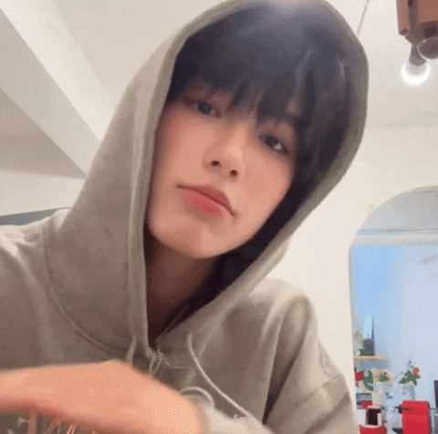 a young man wearing a hoodie is taking a selfie in a room .