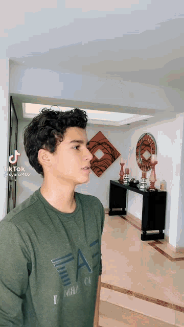 a young man wearing a green t-shirt that says ae on it