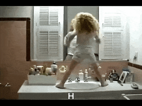 a little girl is dancing in front of a bathroom sink .