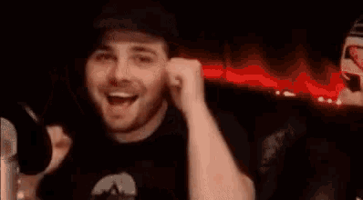 a man is sitting in front of a microphone with his fist in the air and smiling .