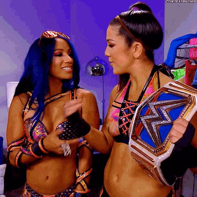 two women are standing next to each other and one of them is holding a championship belt