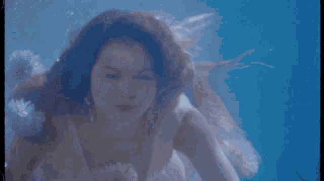 a woman in a white dress is swimming underwater in a pool
