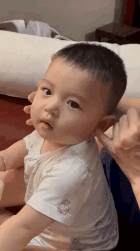 a baby is sitting on a bed and looking at the camera .