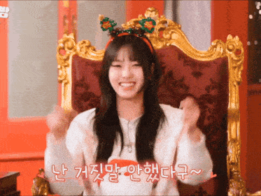 a girl wearing a reindeer headband is sitting in a gold chair