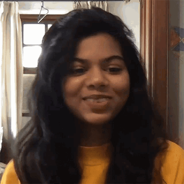 a close up of a woman 's face with a yellow shirt on