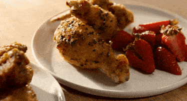 a plate of chicken and strawberries on a table