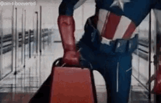 a man in a superhero costume is standing next to a chair .