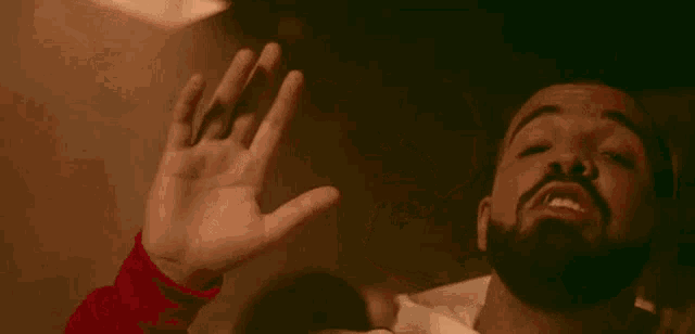 a close up of a man with a beard holding his hand to his face .
