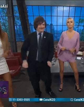 a man in a suit and tie is dancing in front of two women