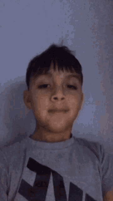 a young boy wearing a grey nike shirt making a face