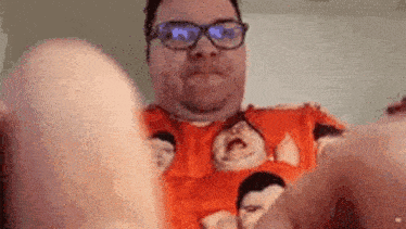 a man wearing glasses and a sweater with a picture of a man on it is holding a banana .