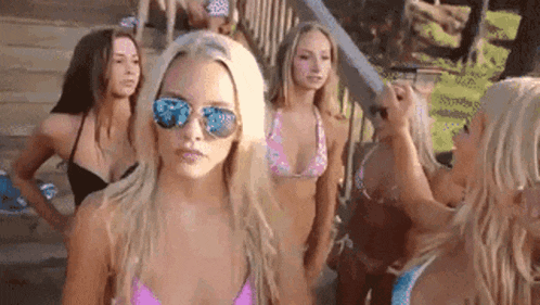 a group of women in bikinis are standing next to each other on a beach .