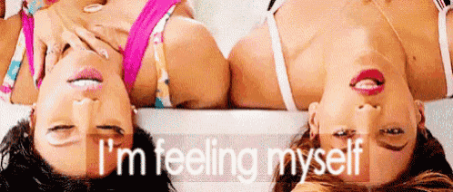 two women are laying upside down on a bed with the words `` i 'm feeling myself '' written on the bottom .