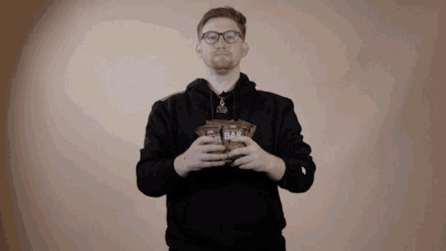 a man in a black hoodie is holding a bag of oat bars