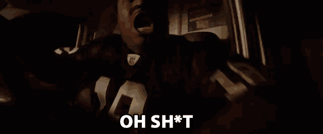 a man in a football jersey is screaming in a dark room with his mouth open .
