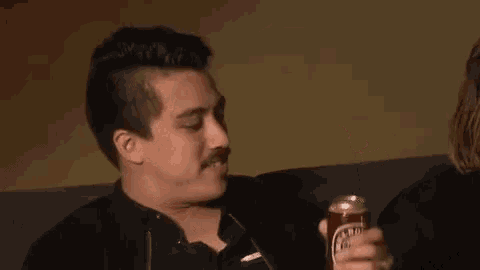 a man is sitting on a couch holding a can of soda in his hand .