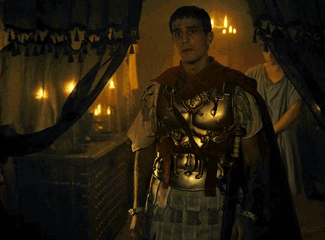 a man dressed as a roman soldier stands in a dark room