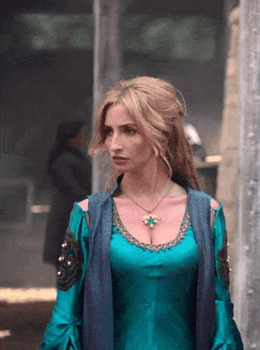a woman in a blue dress has a necklace with a flower on it